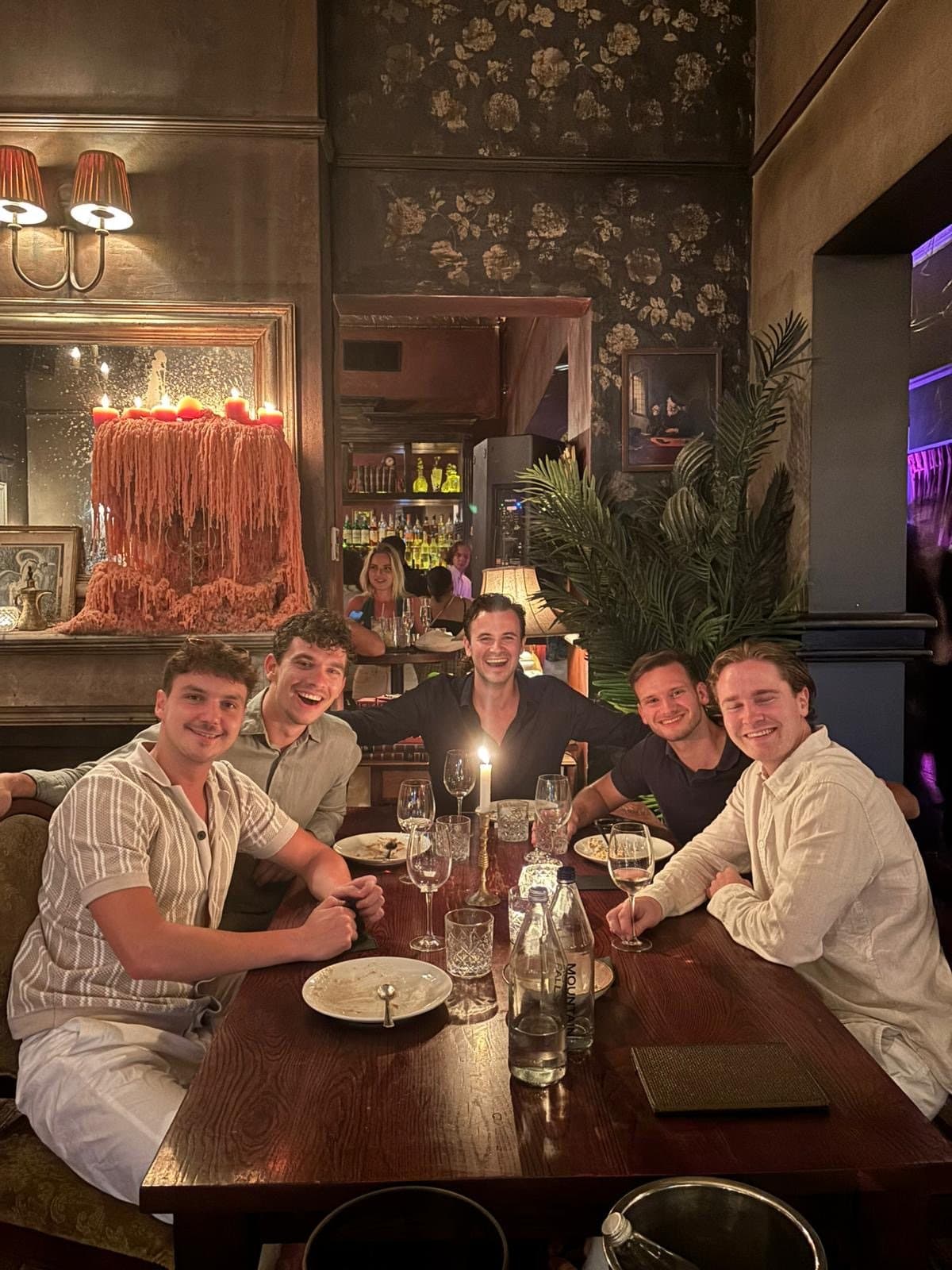 Five founders laughing at a candlelit dinner